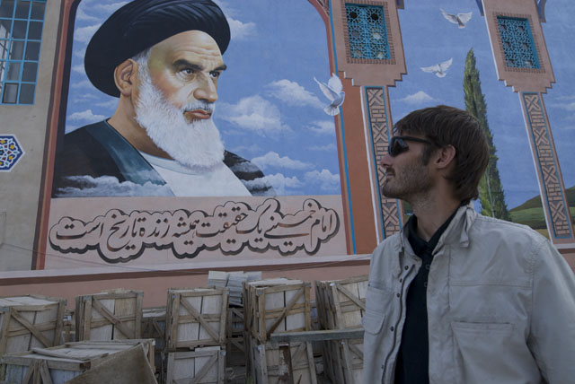 Matthew VanDyke looking at a poster of Ayatollah Khomeini in Iran
