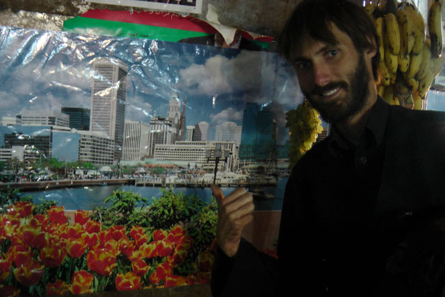 Matthew VanDyke next to a poster of his hometown Baltimore Maryland on a wall in Kabul Afghanistan