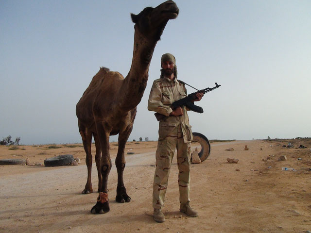 Freedom fighter Matthew VanDyke with his AK-47 and a camel in Sirte Libya