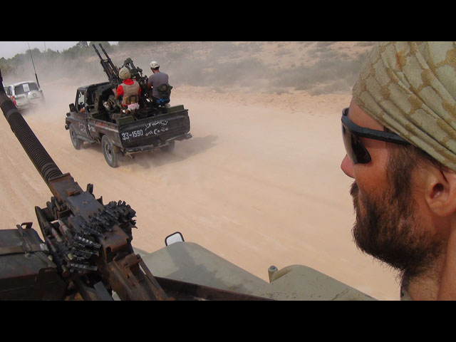 Freedom fighter Matthew VanDyke with a DShK heavy machine gun in the turret of his KADBB Desert Iris jeep during an escort mission in Sirte Libya