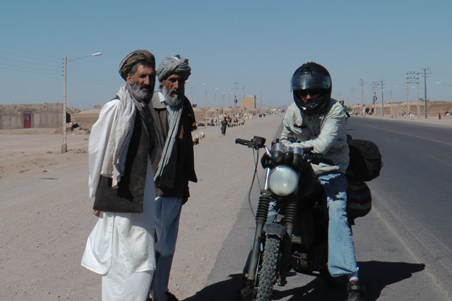 Matthew VanDyke on his MZ Kanuni motorcycle next to Afghan civilians in Afghanistan