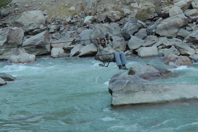 Matthew VanDyke pulling himself along a cable to cross the Panjshir River in Afghanistan